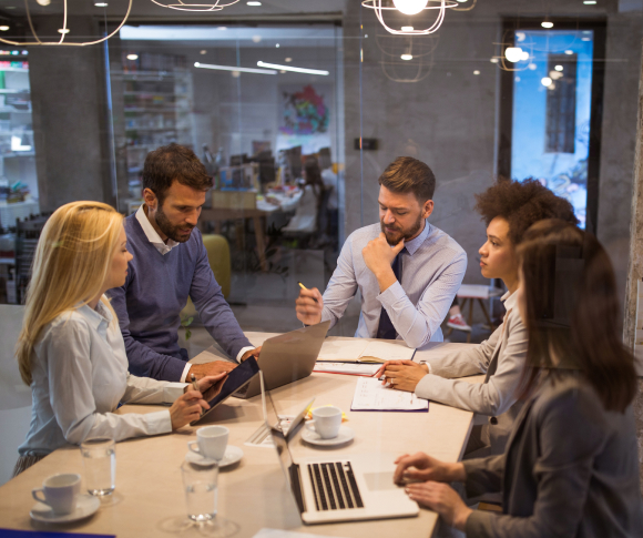 Five people sitting around a table for a brainstorming session.