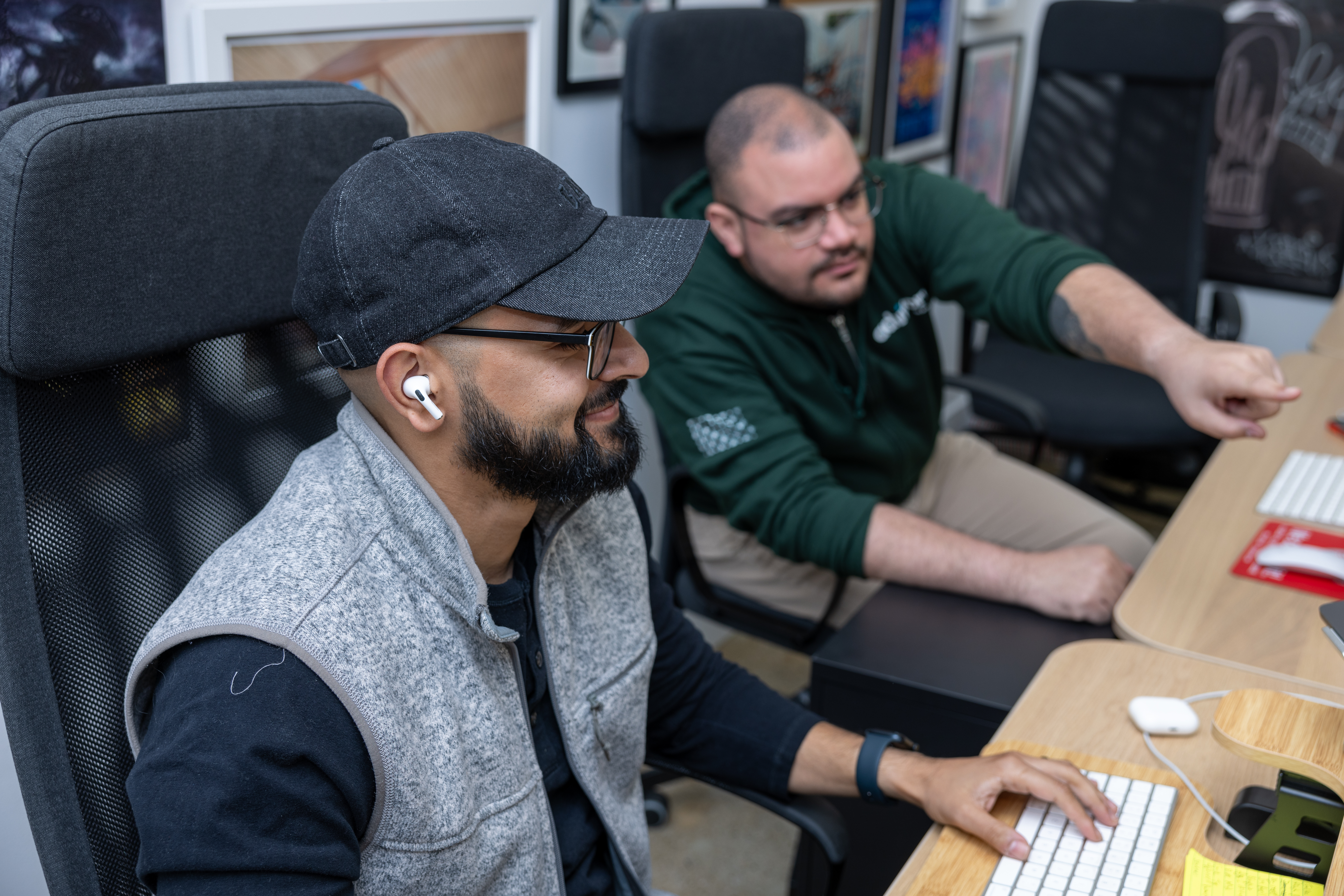 A man pointing to a computer sitting across from a man and a women looking at a computer monitor.